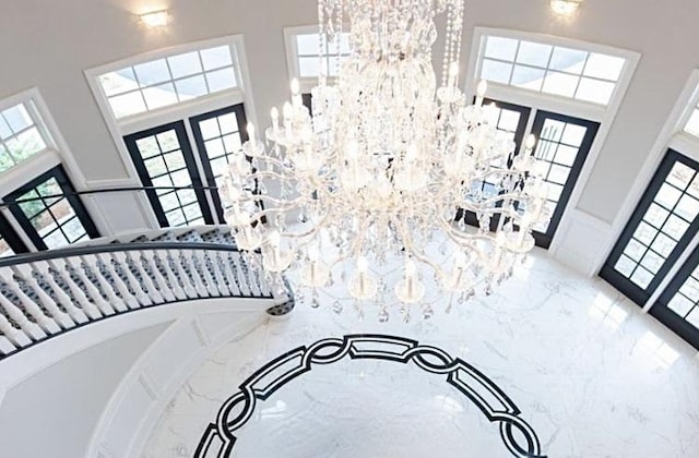 foyer entrance with a towering ceiling, a chandelier, and french doors