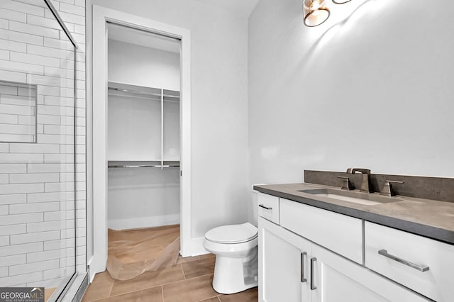 bathroom with toilet, vanity, tiled shower, and tile flooring