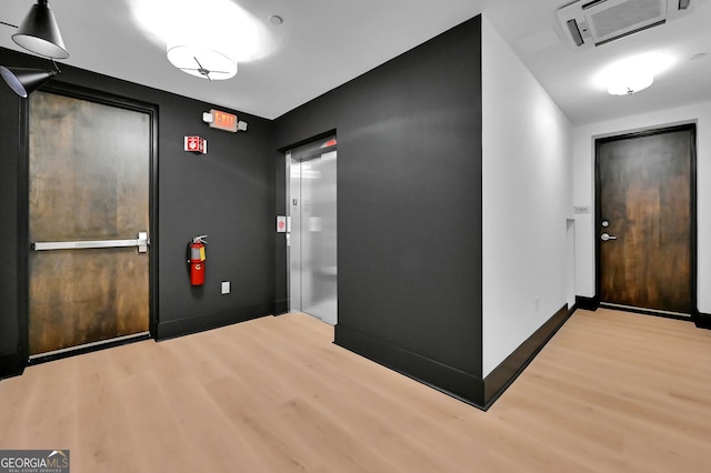 hallway featuring elevator and light wood-type flooring