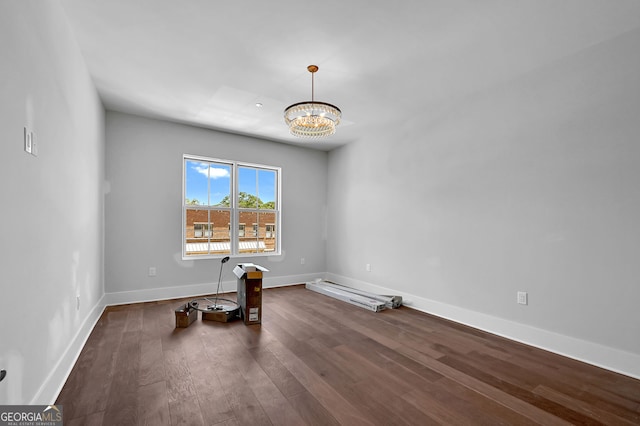 empty room featuring a notable chandelier and dark wood-type flooring