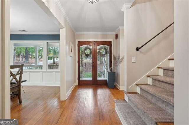 entrance foyer featuring crown molding, french doors, and light hardwood / wood-style flooring