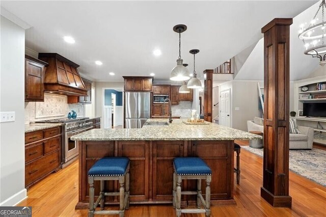 kitchen with custom range hood, tasteful backsplash, light hardwood / wood-style flooring, a large island, and stainless steel appliances