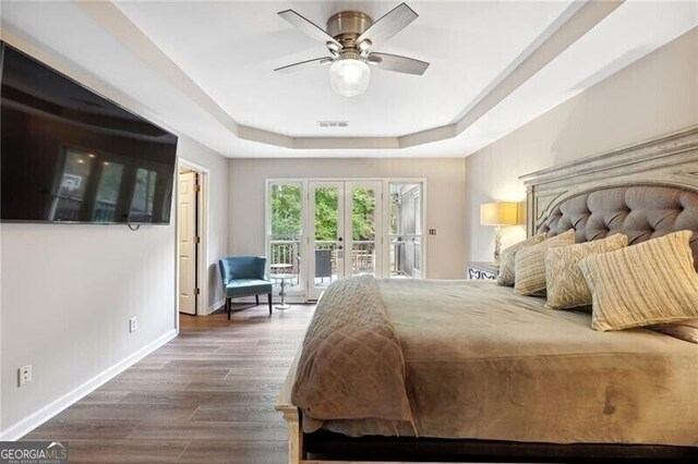 bedroom with hardwood / wood-style flooring, ceiling fan, french doors, a raised ceiling, and access to exterior