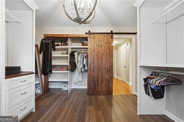 spacious closet featuring a barn door, dark hardwood / wood-style floors, and a chandelier