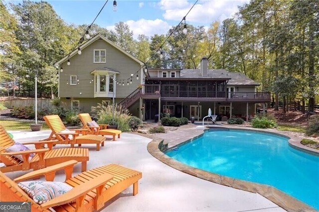 rear view of property featuring a swimming pool side deck and a patio area