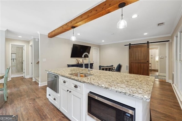 kitchen featuring white cabinets, pendant lighting, stainless steel microwave, and a barn door