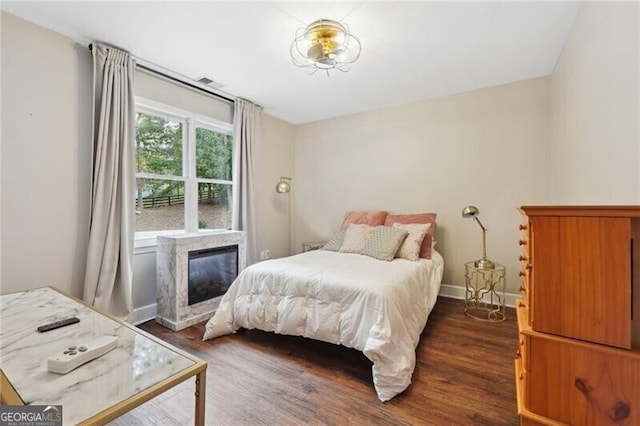 bedroom featuring a premium fireplace and dark hardwood / wood-style flooring