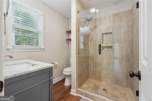 bathroom with hardwood / wood-style floors, vanity, walk in shower, and toilet