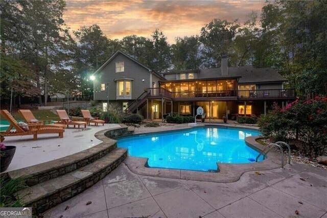 pool at dusk featuring a patio