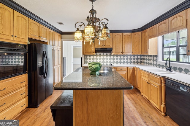 kitchen featuring a center island, hanging light fixtures, light hardwood / wood-style flooring, black appliances, and tasteful backsplash