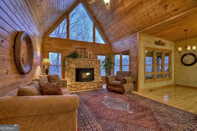 living room with ceiling fan with notable chandelier, a wealth of natural light, a fireplace, and wood-type flooring