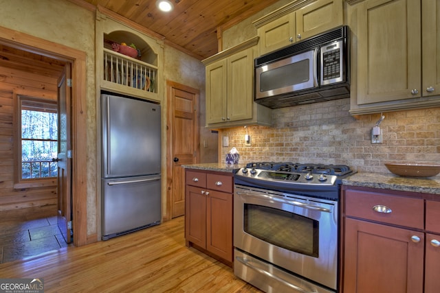 kitchen with appliances with stainless steel finishes, backsplash, dark stone counters, and light hardwood / wood-style flooring