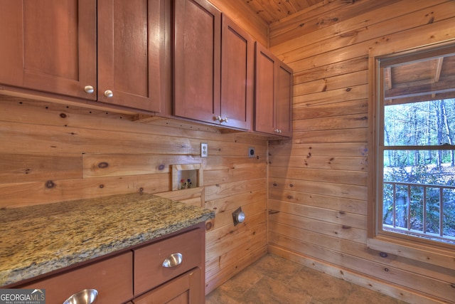 kitchen with wood walls, light stone countertops, and wooden ceiling