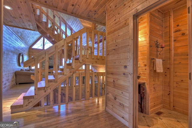 stairway with wood ceiling, lofted ceiling, hardwood / wood-style floors, and wood walls