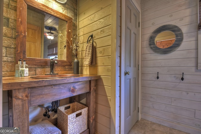 bathroom featuring tile patterned flooring, wooden walls, and vanity