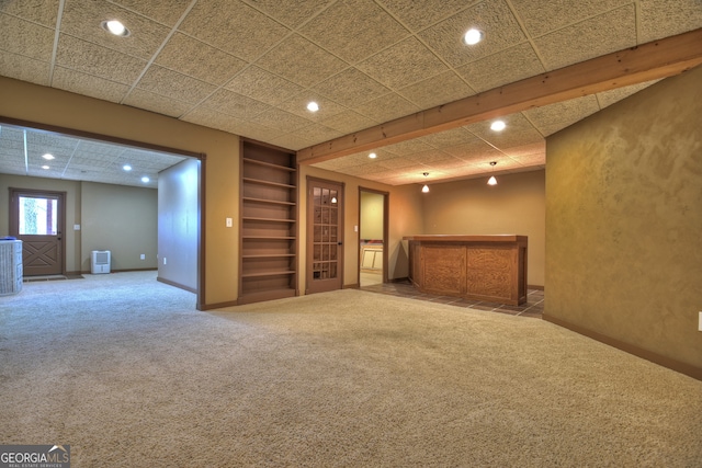 basement featuring built in shelves and carpet