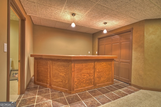 bar featuring a paneled ceiling, pendant lighting, and dark colored carpet