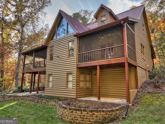 back of house with a sunroom, a patio area, and a lawn