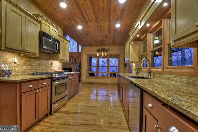 kitchen with light hardwood / wood-style flooring, appliances with stainless steel finishes, sink, a chandelier, and light stone counters