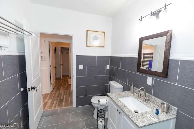 bathroom featuring tile walls, hardwood / wood-style floors, toilet, and vanity