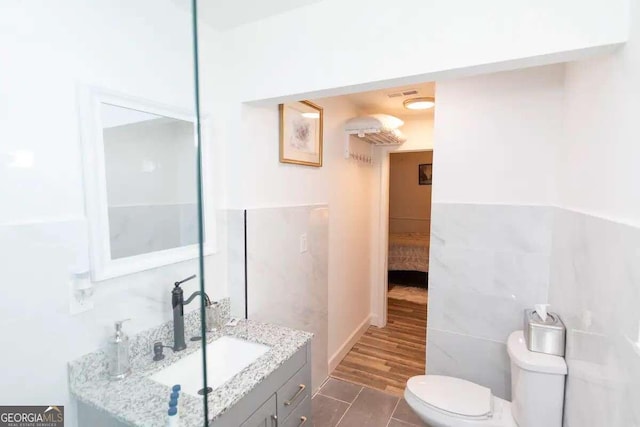 bathroom with hardwood / wood-style floors, oversized vanity, toilet, and tile walls