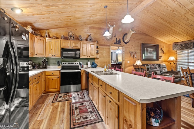 kitchen with decorative light fixtures, lofted ceiling, black appliances, sink, and wooden walls