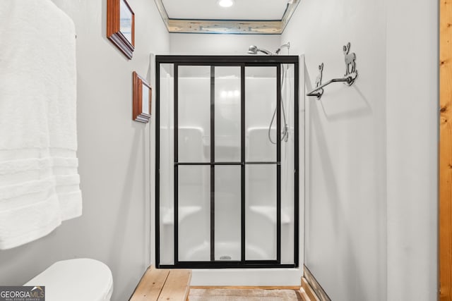 bathroom featuring toilet, wood-type flooring, and a shower with shower door