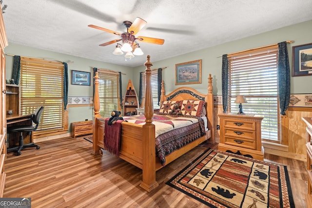 bedroom with multiple windows, a textured ceiling, ceiling fan, and light wood-type flooring