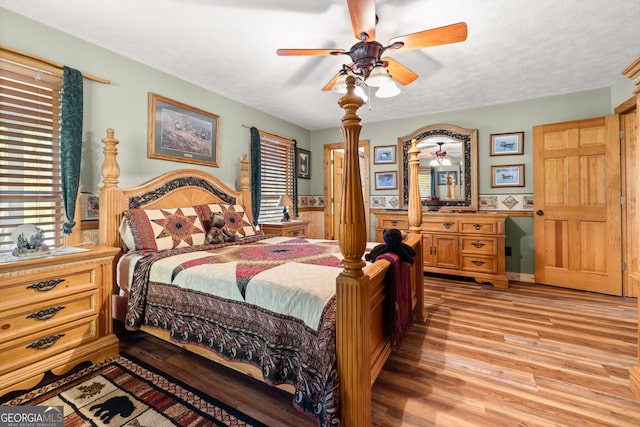 bedroom with ceiling fan, light hardwood / wood-style flooring, and a textured ceiling