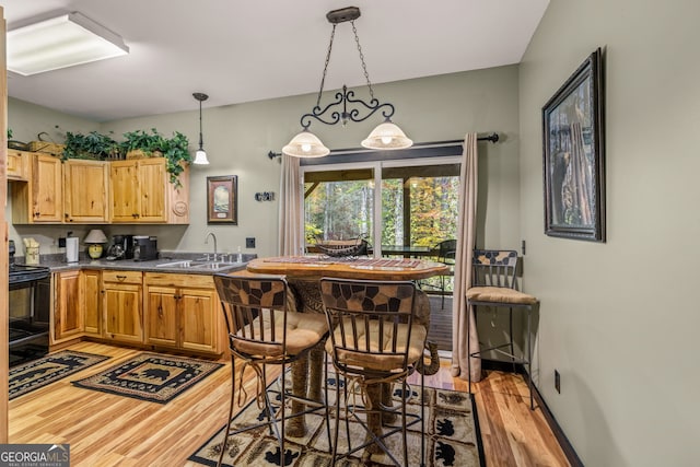 kitchen featuring decorative light fixtures, electric range, sink, light hardwood / wood-style flooring, and a chandelier