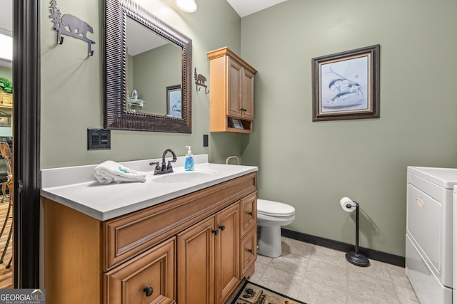 bathroom with toilet, tile flooring, washer / dryer, and vanity with extensive cabinet space