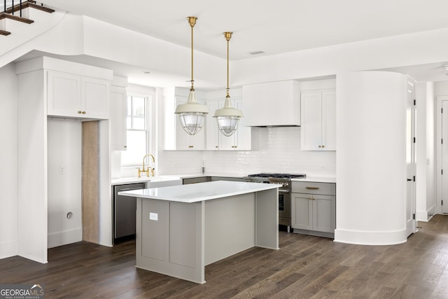 kitchen with hanging light fixtures, a kitchen island, stainless steel appliances, and dark hardwood / wood-style flooring