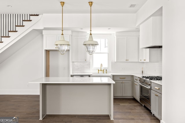 kitchen featuring high end stainless steel range, backsplash, dark hardwood / wood-style flooring, a kitchen island, and sink