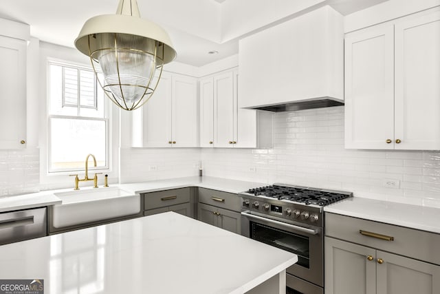 kitchen with backsplash, appliances with stainless steel finishes, light stone counters, sink, and gray cabinets