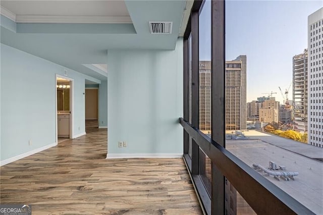 interior space with a tray ceiling, ornamental molding, and hardwood / wood-style flooring