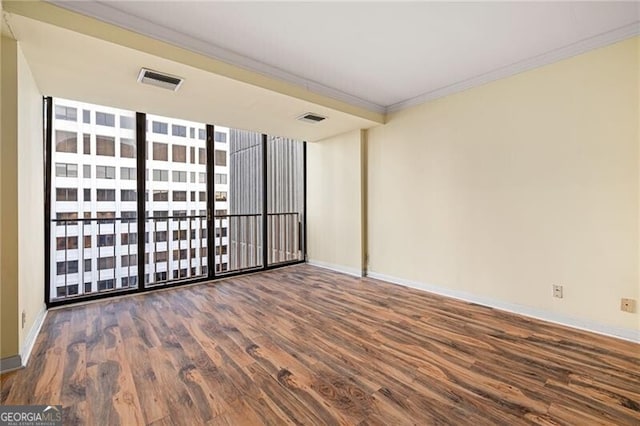 empty room featuring crown molding, a wall of windows, and dark wood-type flooring