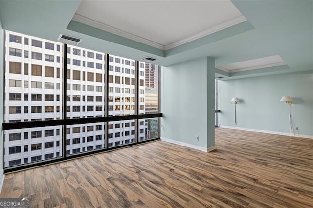 unfurnished room with hardwood / wood-style floors, a raised ceiling, and crown molding