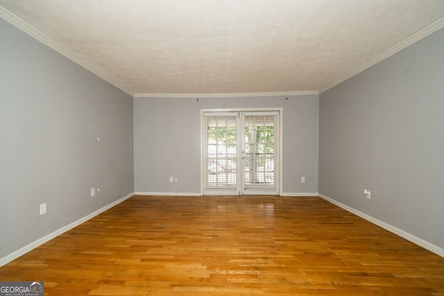 empty room with ornamental molding, light hardwood / wood-style flooring, and a textured ceiling