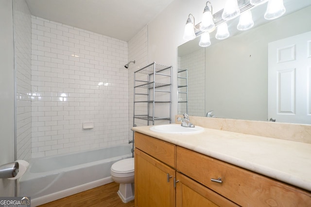 full bathroom with tiled shower / bath, vanity, hardwood / wood-style flooring, and toilet