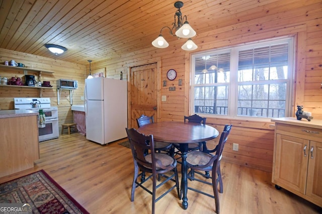 dining space with wooden walls, light hardwood / wood-style flooring, and wooden ceiling