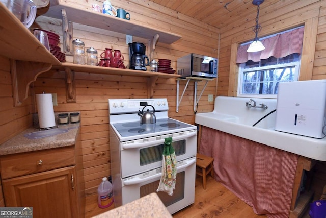 kitchen featuring decorative light fixtures, wood walls, light wood-type flooring, and white range with electric stovetop