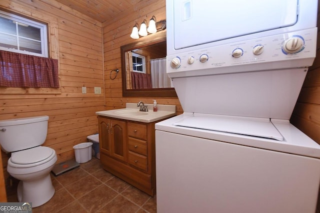 interior space with wood walls, vanity, toilet, and tile floors