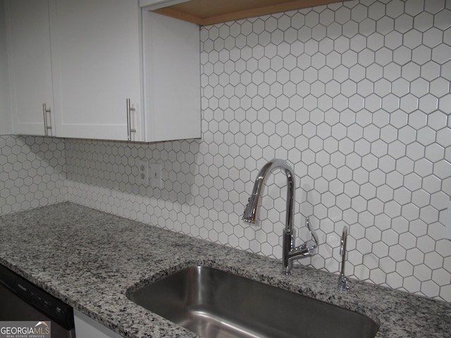 kitchen with light stone countertops, backsplash, sink, white cabinets, and stainless steel dishwasher