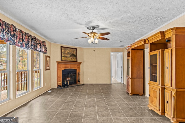 unfurnished living room featuring tile flooring, ornamental molding, ceiling fan, and a textured ceiling