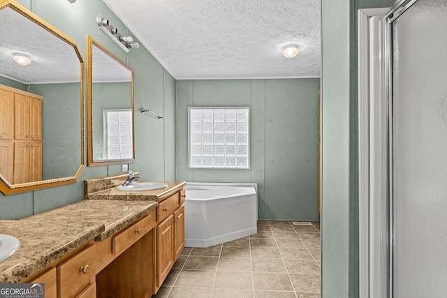 bathroom with a textured ceiling, tile flooring, vanity, and a tub