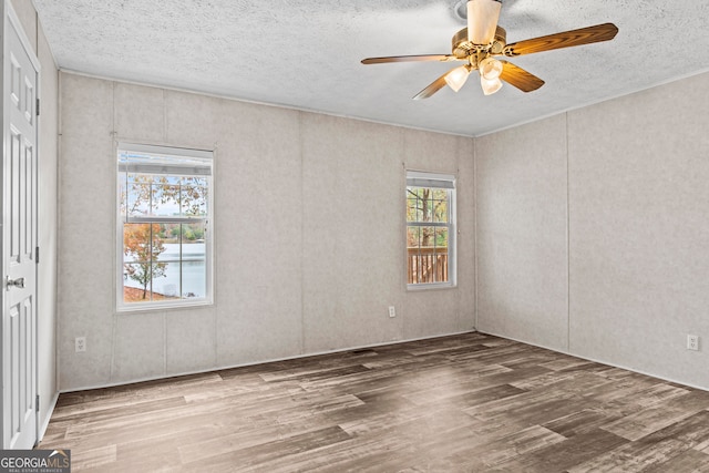 empty room featuring ceiling fan, hardwood / wood-style flooring, and a textured ceiling