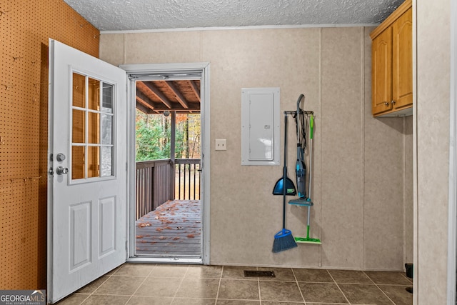 doorway to outside featuring a textured ceiling and light tile floors