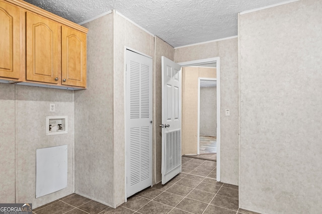 washroom featuring hookup for a washing machine, dark tile flooring, a textured ceiling, and cabinets