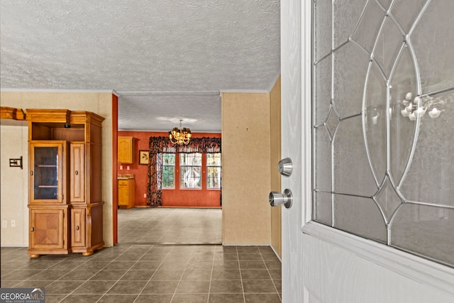 entrance foyer featuring a notable chandelier, dark tile flooring, and a textured ceiling