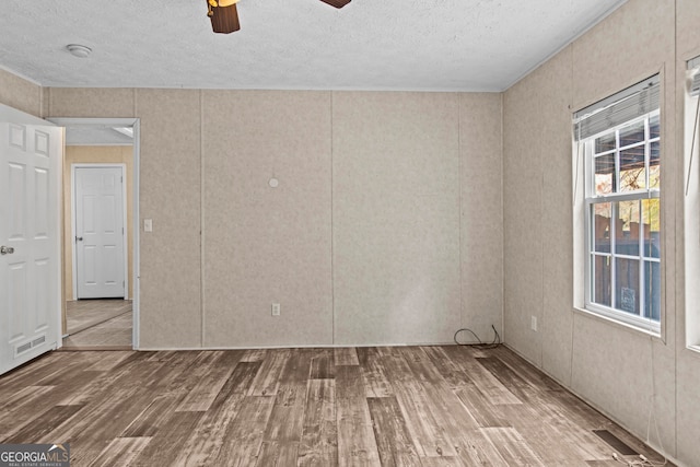 empty room with a textured ceiling, ceiling fan, and hardwood / wood-style floors